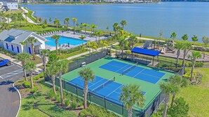 A tennis court surrounded by palm trees and a pool area. - New! Waterside Lakewood Ranch, Tennis, Pool, Walk to Restaurants and More! (Sarasota)
