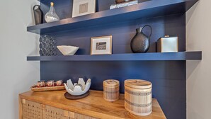 A wooden cabinet with decorative items and a blue wall with shelves. - New! Waterside Lakewood Ranch, Tennis, Pool, Walk to Restaurants and More! (Sarasota)