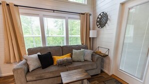 Ein Wohnzimmer mit einer Couch, einem Couchtisch und einem fenster mit Vorhängen.