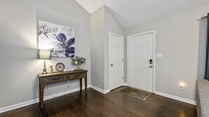 A hallway with a wooden console table, a wall-mounted lamp, a floral painting, and a set of white doors. - 10 Jill Lane, Cartersville (Cartersville)