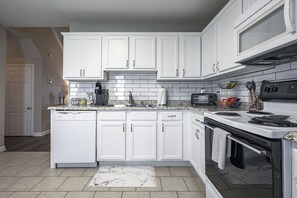 A modern kitchen with white cabinetry, a built-in oven, a microwave, and a coffee maker. - 31 Middleton Court Cartersville (Cartersville)