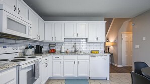 Una cocina moderna con armarios blancos, microondas integrado, estufa y lavavajillas.
