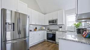A modern kitchen with white cabinets, stainless steel appliances, and a granite countertop.
