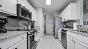 Une cuisine moderne avec des meubles blancs, des appareils en acier inoxydable et un carrelage décoratif.