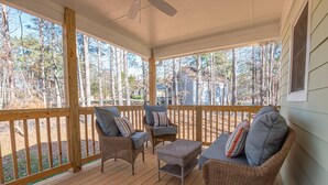 A covered porch with wicker furniture and a view of a forested area. - 27 West Ridge Drive SE, Cartersville (Cartersville)