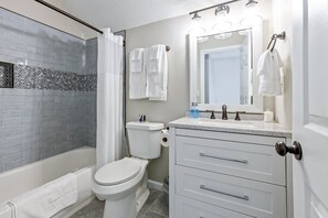 A modern bathroom with a bathtub, toilet, and vanity with a mirror. - 13 Windfield Dr, Cartersville (Cartersville)