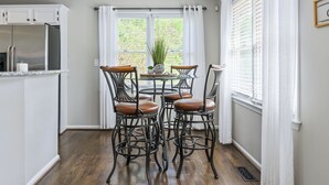 Een eetgedeelte met een ronde tafel, vier stoelen en een plafondlamp.