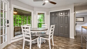 A dining area with a round table, white chairs, and a ceiling fan.