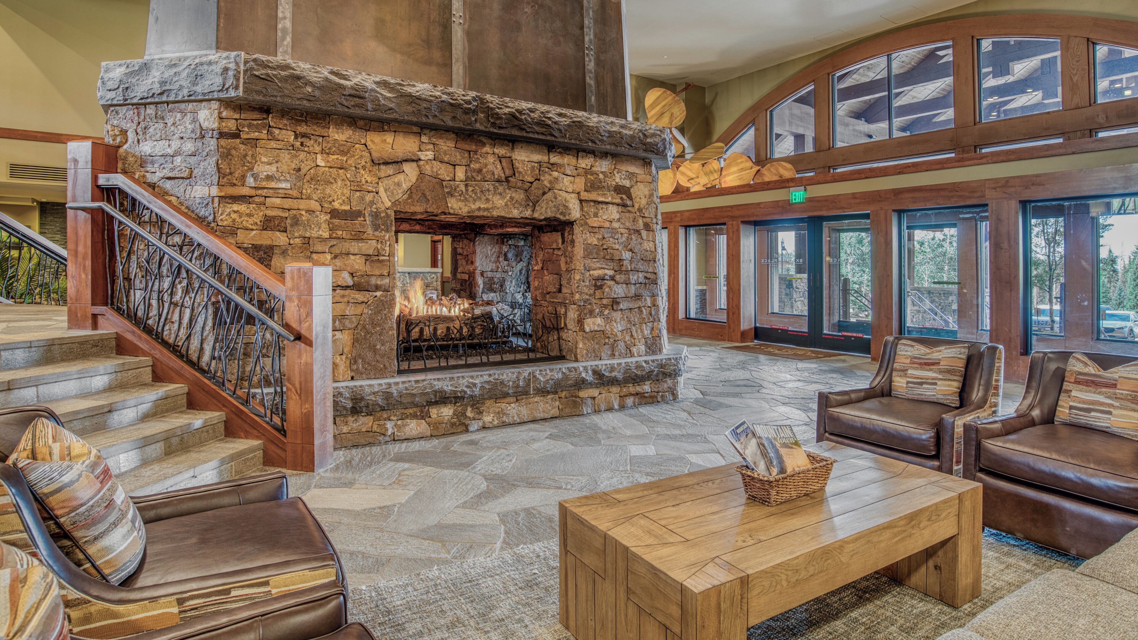A lobby with a stone fireplace, leather seating, and a staircase.