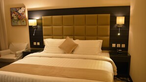 A hotel room with a large bed, two bedside lamps, a headboard, and a painting on the wall. - فندق مرسى القصر Marsa Alqaser Hotel (Madinah)