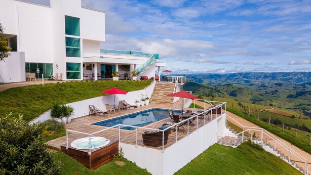 A modern house with a swimming pool, outdoor seating, and a scenic view. - Unique Alta Vista Pousada Boutique (Córrego do Bom Jesus)