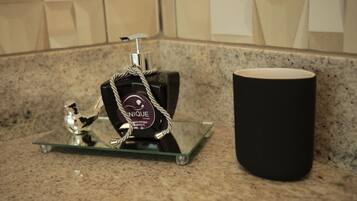 A bathroom counter with a glass soap dispenser and a black candle holder.