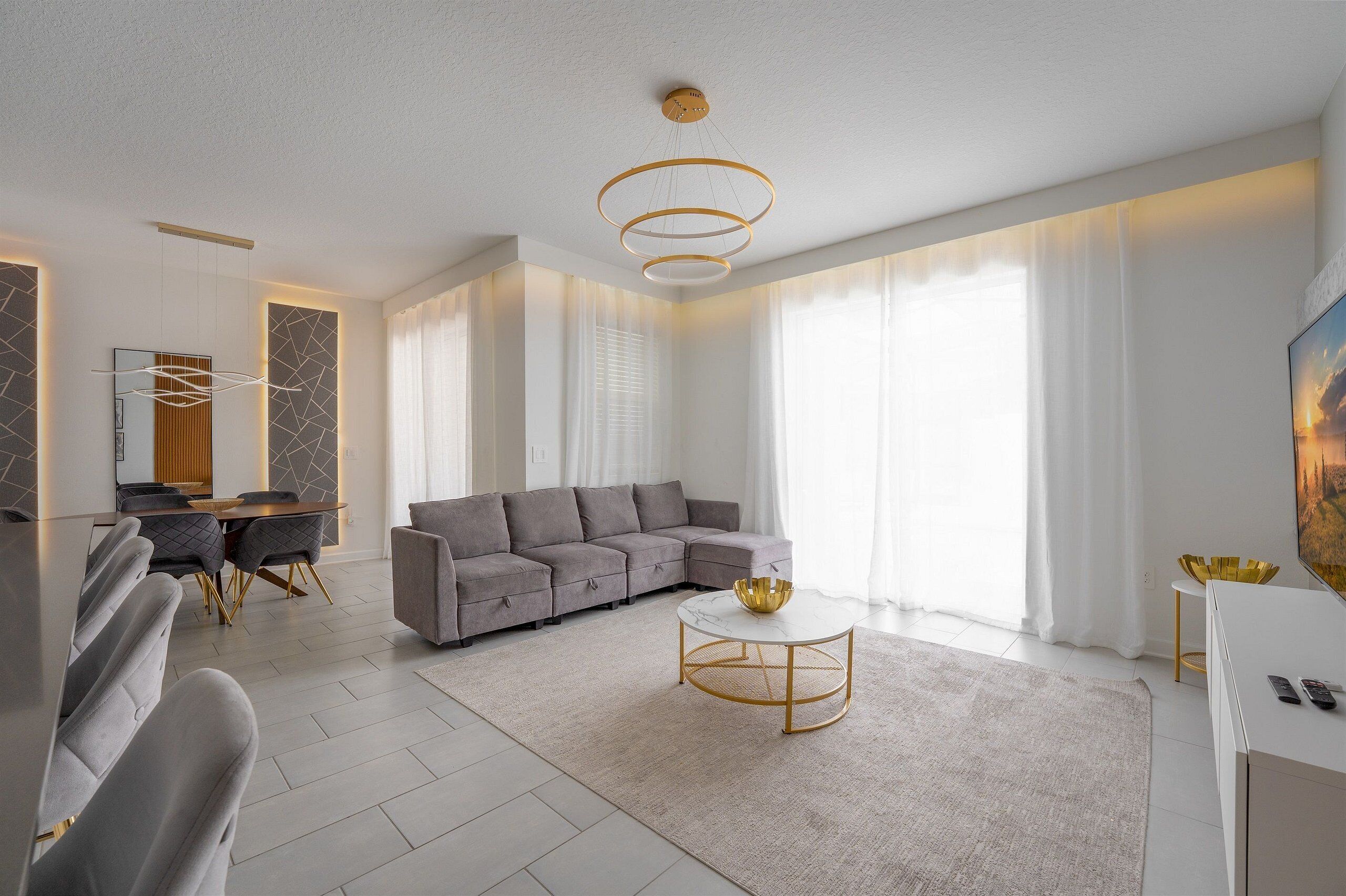 A modern living room with a sectional sofa, a round coffee table, and a dining area with a table and chairs.