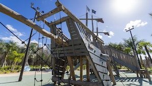 A wooden play structure with ropes and a slide, surrounded by palm trees and a clear sky. - Storey Lake Resort 4BR Home w/ Private Pool (Kissimmee)