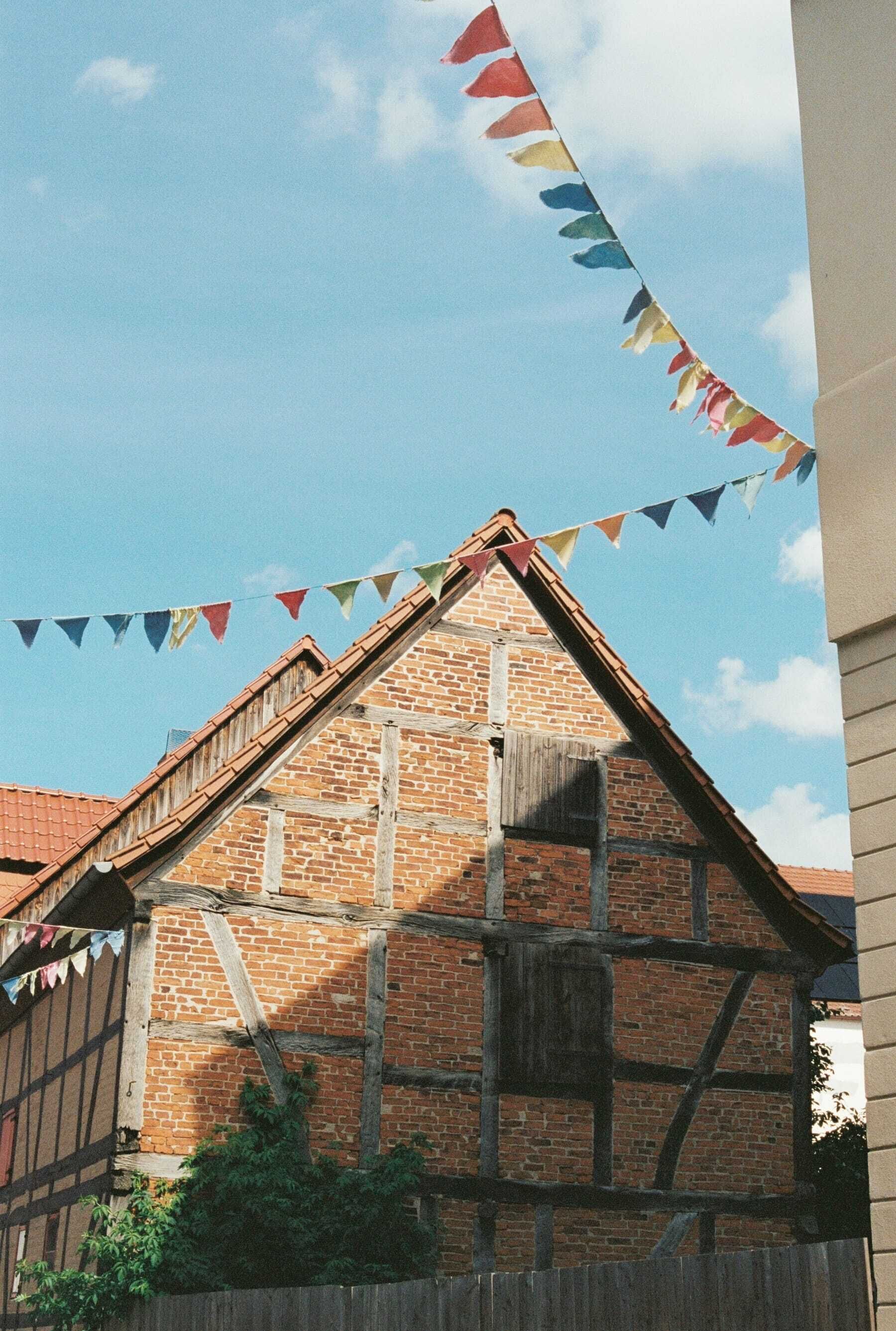 A traditional half-timbered building with a steeply pitched roof and a wooden staircase leading to the entrance.