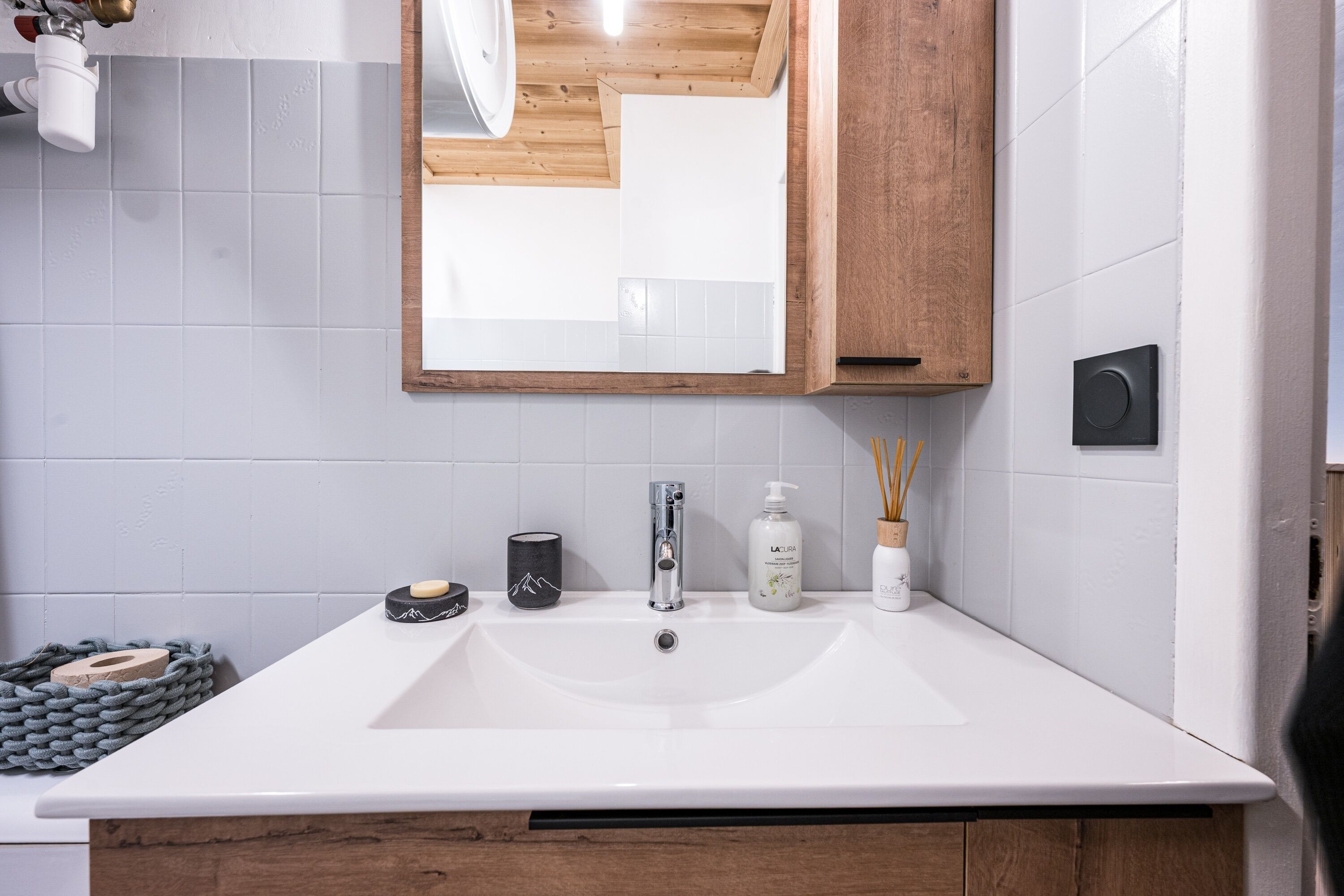 A bathroom with a white sink, a mirror, and a wooden cabinet.