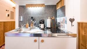 Una cocina moderna con un lavamanos de acero inoxidable, armarios de madera y una cafetera.