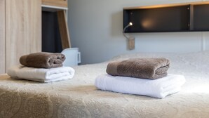 Cama bem arrumada com toalhas dobradas em quarto de hotel.