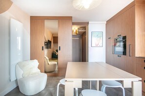Eine moderne Küche mit großem Tisch, weißen Stühlen und Holzschränken.