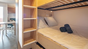 Una cama individual con cabecera de madera, un escritorio y una silla en la habitación contigua.