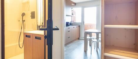 A modern kitchen with wooden cabinets, a dining table, and a view of the outdoors.