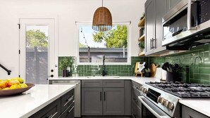 A modern kitchen with grey cabinets, a stainless steel stove, and a window with a view of the outside.