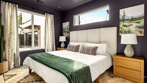 A bedroom with a large bed, two bedside tables, a ceiling fan, and a window with curtains.