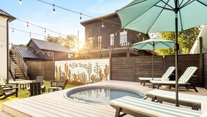 A backyard with a swimming pool, lounge chairs, and a wooden deck.