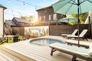 A backyard with a swimming pool, lounge chairs, and a wooden deck. - Sleeps 12, Pool, Games, Fun, Mins from Downtown (Austin)