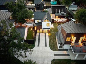 A modern residential area with a central house featuring a prominent garage, a driveway, and a well-maintained lawn. - Sleeps 12, Pool, Games, Fun, Mins from Downtown (Austin)