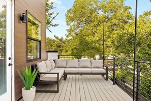 A balcony with a sofa, a potted plant, and a railing. - Sleeps 12, Pool, Games, Fun, Mins from Downtown (Austin)