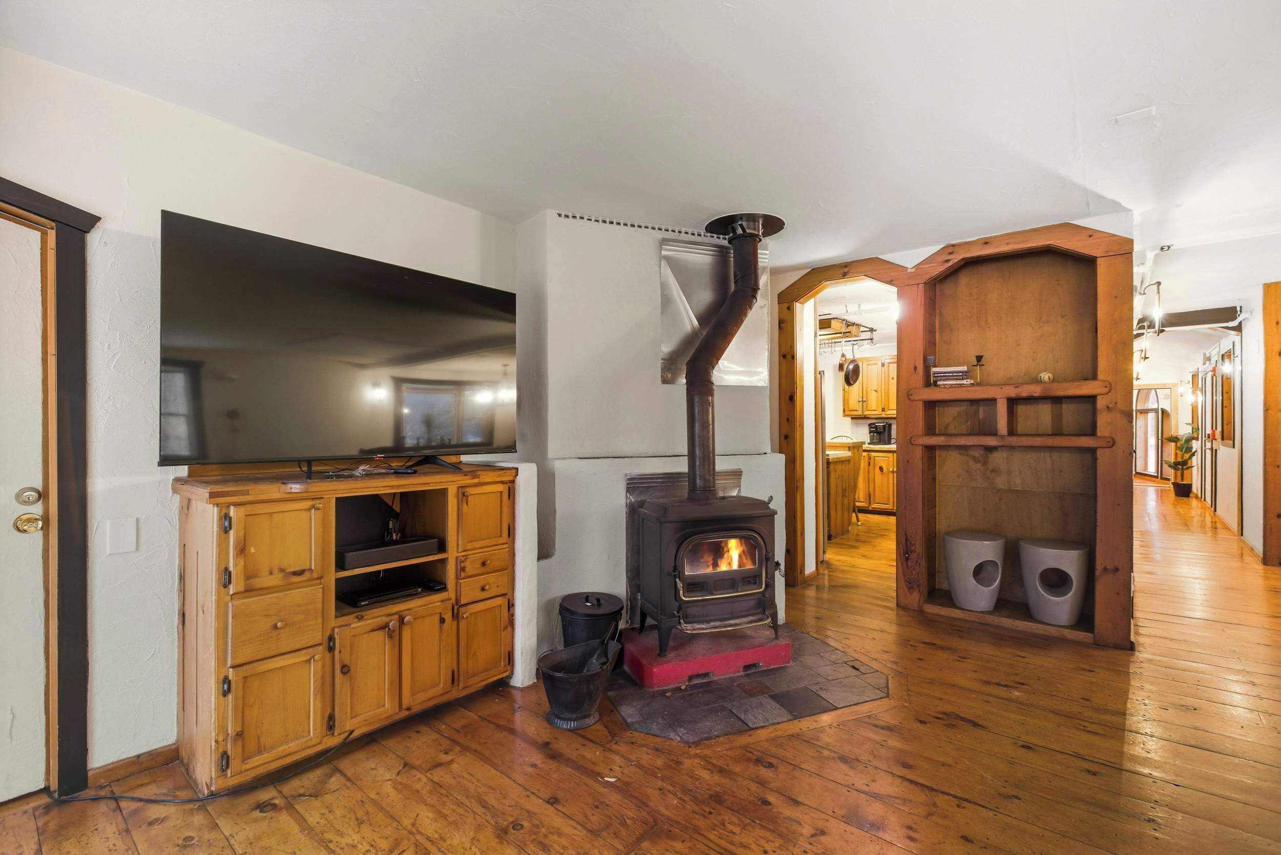 A kitchen with a wood-burning stove, wooden cabinets, and a television.