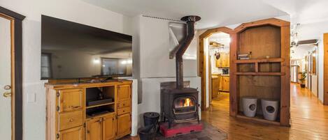 A kitchen with a wood-burning stove, wooden cabinets, and a television.