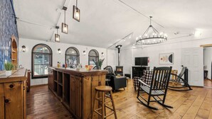 A spacious kitchen with wooden flooring, a central island, and a dining area with chairs and a fireplace.