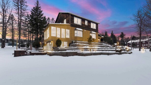 A two-story wooden house with a snow-covered front yard and steps leading up to the entrance.