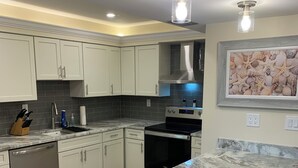 A modern kitchen with white cabinets, a marble countertop, and a stainless steel range hood. - ATTENTION GOLF LOVERS / HAMMOCK BAY GOLF COURSE, NAPLES FL./ CLOSE TO BEACHES (Naples)