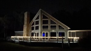 Un edificio grande de varios pisos con una chimenea destacada, múltiples ventanas y un exterior bien iluminado.