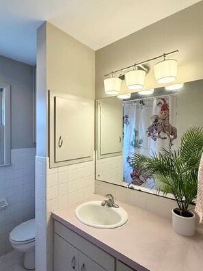 A bathroom with a white sink, a mirror, and a shower curtain with a floral design. - The Shameless Cowboy: Stillwater, OK (Stillwater)