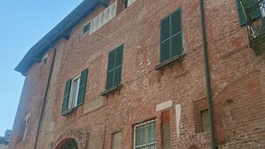 Un bâtiment en briques rouges doté de trois fenêtres, chacune ornée de volets verts.