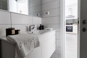 A modern bathroom with a white vanity, a towel, and a bottle of hand soap.