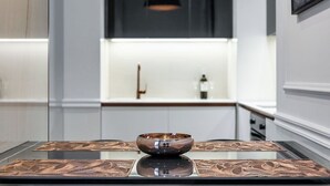 Une cuisine moderne dotée d’un îlot central, d’un luminaire suspendu noir et d’un pare-feu blanc.