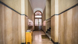 Un pasillo con suelo de madera, un banco de madera con libros y una escalera con barandilla.