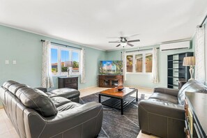 A living room with two leather sofas, a coffee table, and a ceiling fan.