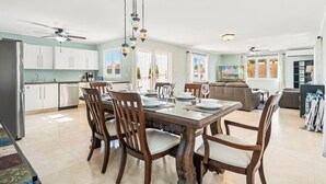 A spacious kitchen with white cabinets, a dining table set for four, and a ceiling fan. - Private Pool! Rooftop with Ocean View! (Savaneta)