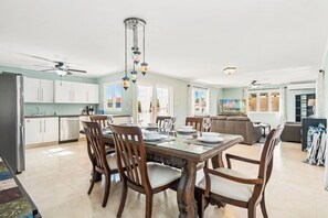 A spacious kitchen with white cabinets, a dining table set for four, and a ceiling fan.