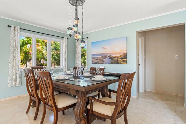 A dining area with a wooden table set for four, surrounded by chairs with cushioned seats.