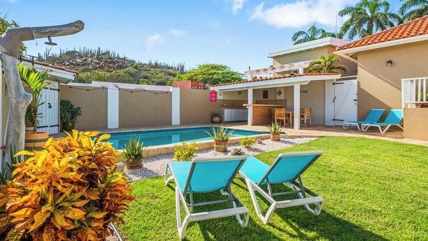 A poolside area with lounge chairs, a small pool, and a patio with a table and chairs. - Private Pool! Rooftop with Ocean View! (Savaneta)