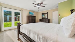 A bedroom with a large bed, a ceiling fan, a dresser, a mirror, and a sliding glass door leading to a balcony. - Private Pool! Rooftop with Ocean View! (Savaneta)