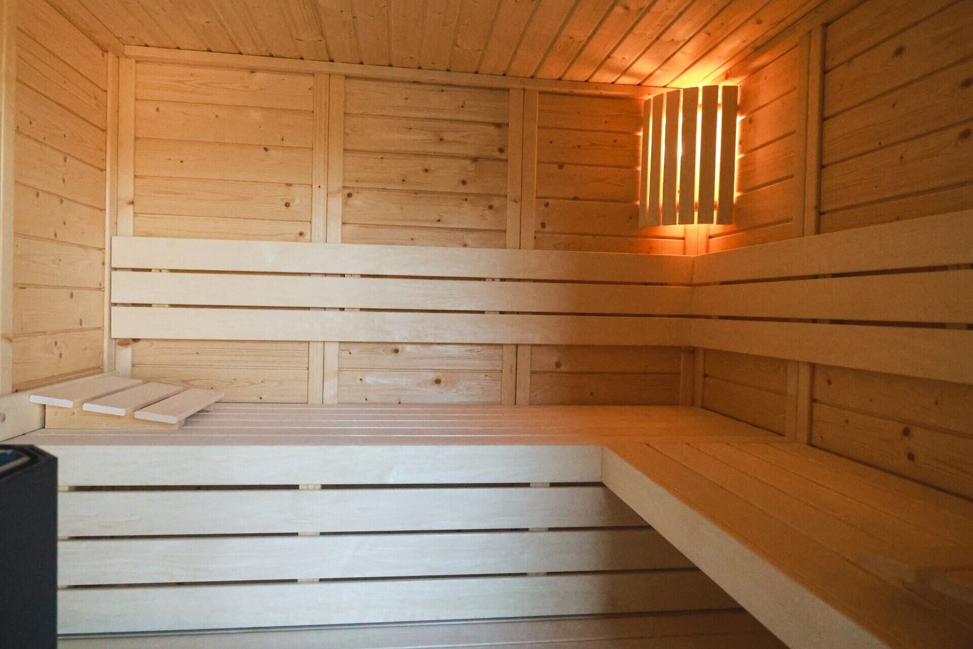 Una sauna de madera con bancos y un aplique en la pared.