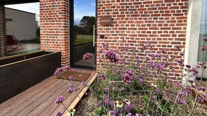 A brick building with a wooden deck and a door labeled "ACCEIL". - Clos du Riez - Suites & SPA (La Gorgue)